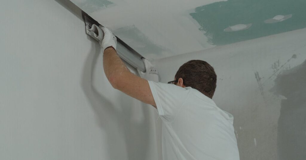 A man works meticulously on drywall installation during a house renovation.